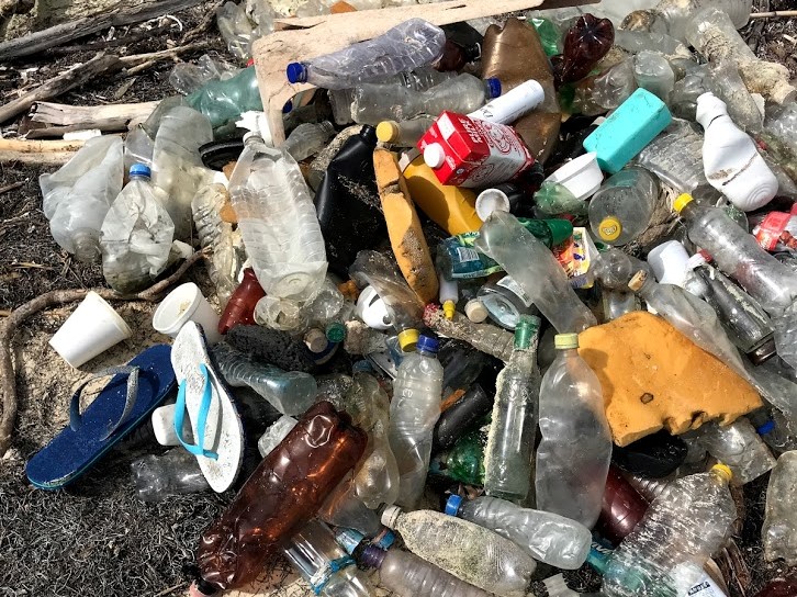 Lots of plastic bottles, shoes and rubbish washed up on a beach