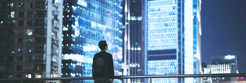 a man on a bridge looking out at the city